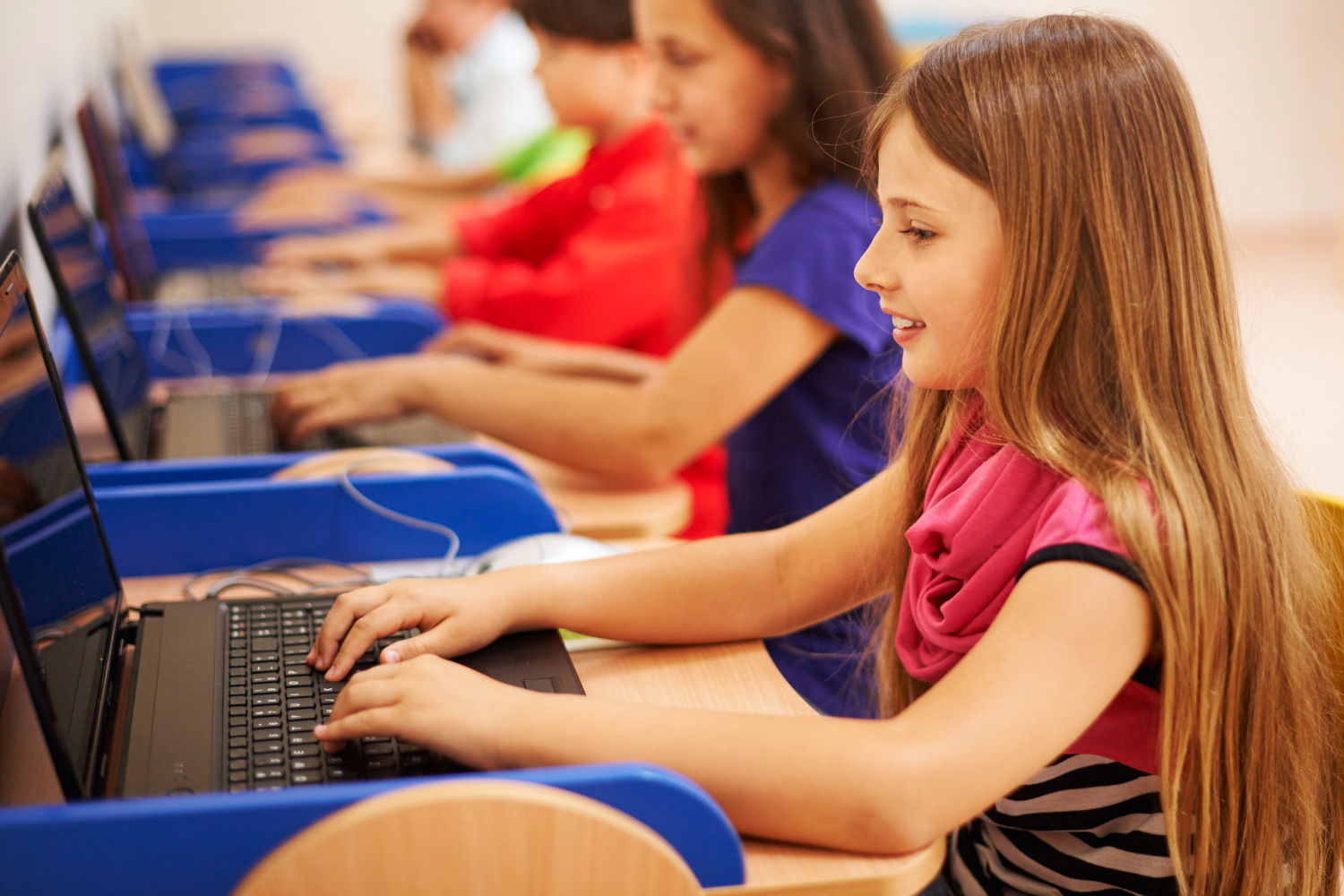 Students in a classroom working on the computer with happiness