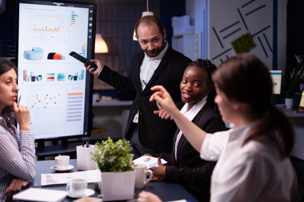 Diverse multi-ethnic business team looking at financial company presentation on monitor.