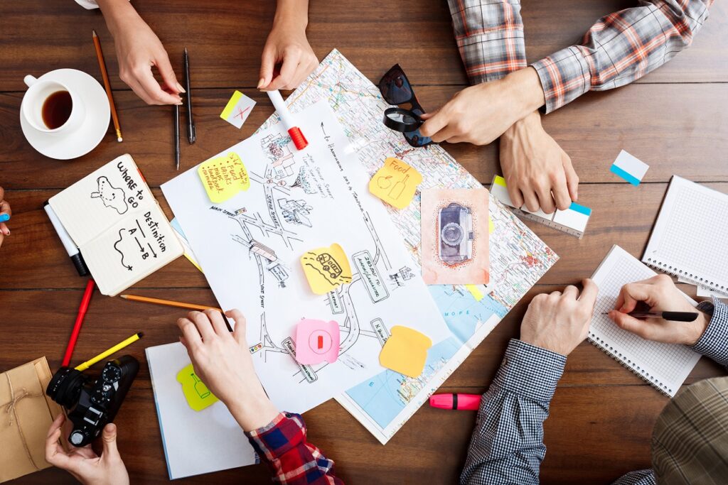 Picture of businessmen's hands on wooden table with documents, coffee and drafts